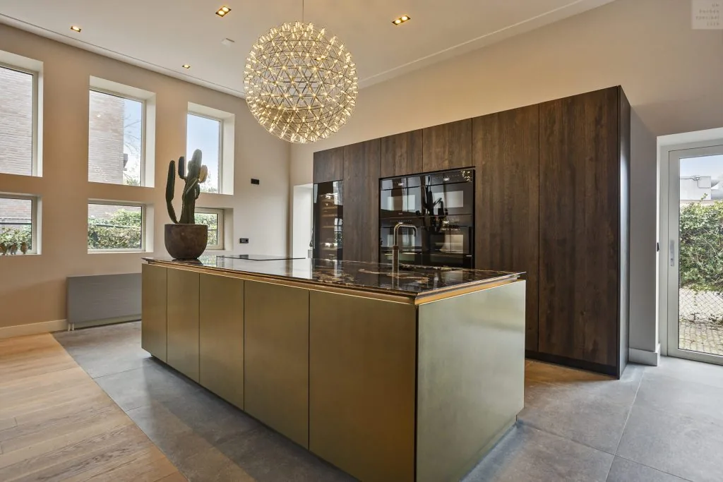 Keuken met koperkleurig kookeiland en donker houten kastenwand
